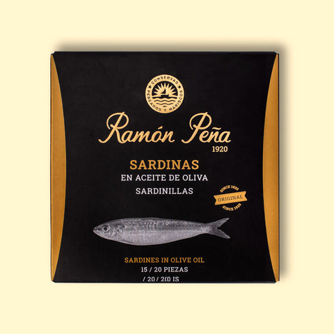 Sardines in olive oil in black and gold card packaging. Ramón Peña is written in raised gold lettering above a silver-grey image of a sardine.