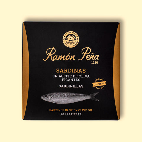 Spicy sardines in black and gold card packaging. Ramón Peña is written in gold lettering above a silver-grey image of a sardine.