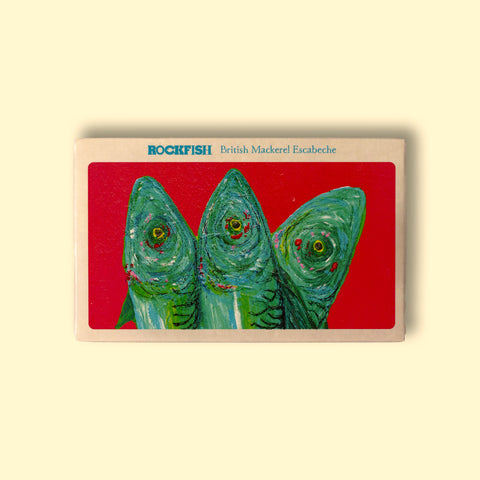 A tin of mackerel in escabeche (vinegar, olive oil and paprika) in off-white card packaging with a painting of three bright green and blue mackerel against a vivid red background beneath Rockfish British Mackerel Escabeche in blue lettering.
