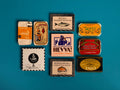 A selection of colourfully-packaged tinned mussels, squid, sardines, herring, tuna and mackerel against a blue background.