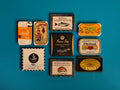 A selection of colourfully-packaged tinned mussels, squid, sardines, herring, tuna and mackerel against a blue background.