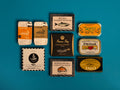 A selection of colourfully-packaged tinned mussels, squid, sardines, herring, tuna and mackerel against a blue background.
