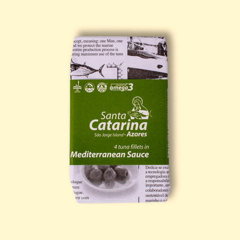 A tin of Santa Catarina tuna in newspaper-style packaging with a green label against a yellow background