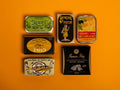 A selection of colourfully packaged tins of sardines and tuna against a yellow background.