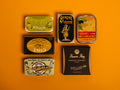 A selection of colourfully packaged tins of sardines and tuna against a yellow background.