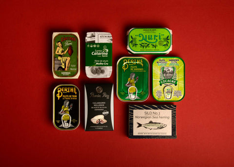 A selection of colourfully packaged tinned fish on a red background