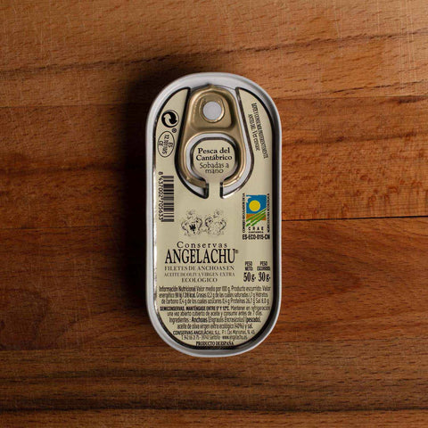 Anchovies in a light-coloured, rectangular tin with rounded edges against a wood background