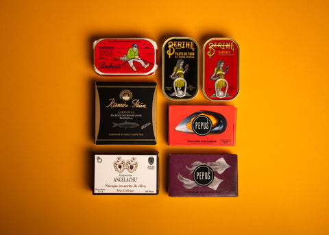 A selection of colourfully packaged tinned fish on a yellow background