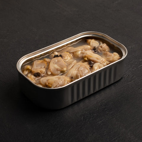 Silver tinned clams in a flavoursome olive oil. accompanied by a crisp black background  