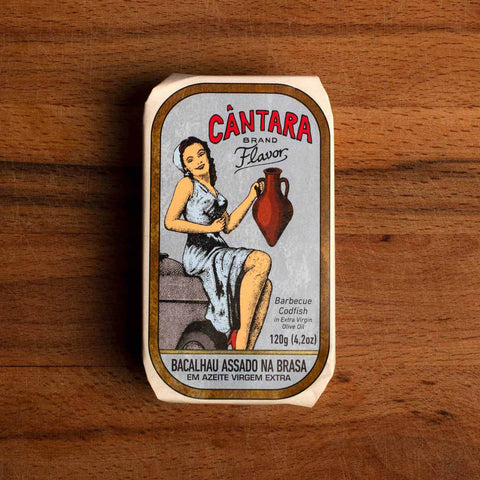 A tin with a woman in a light blue dress holding an amphora of olive oil on the front of the packaging