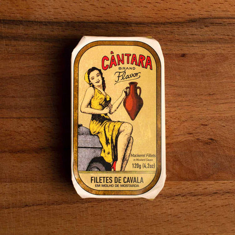 The tin's wrap depicts a woman in a yellow dress holding an amphora of olive oil with Cântara written in red lettering above. The tin is on a wood background