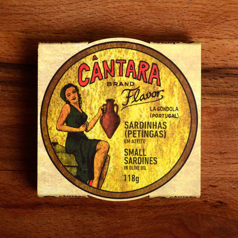 A round tin of small sardines in a card wrap. Cântara is written in red above an image of a woman in a green dress holding an amphora of olive oil on the packaging