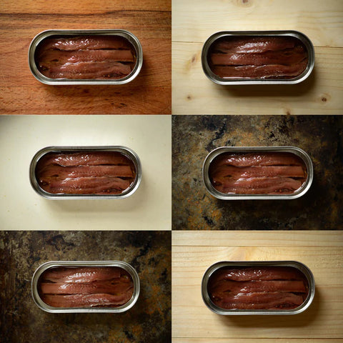 Six different pictures of delicious tinned anchovies open against different backdrops.