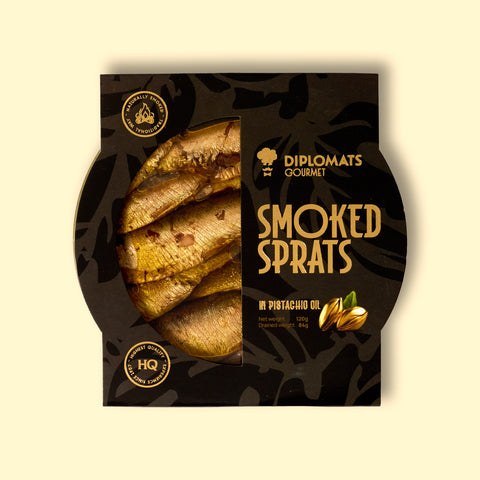 Smoked sprats in pistachio oil, shown in partially open black packaging, with the golden-brown fish visible inside. 