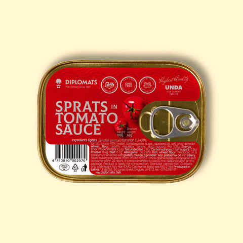 A golden-coloured rectangular tin with a silver ring-pull on the right. The tin is on a pale yellow background. The tin has a red sticker covering its surface with "sprats in tomato sauce" written in white lettering by an image of some tomatoes. The ingredients and nutrients are written at the bottom of the label in small white type.