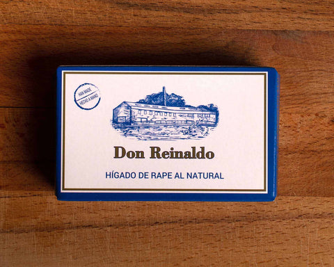 Monkfish liver in a white rectangular box with a blue border and Don Reinaldo written in gold lettering beneath an image of the cannery