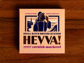 Box containing Cornish mackerel from Hevva! The box is illustrated with a fisherman calling out over the Cornish coast with cliffs and a lighthouse in the background. The box is colourful with the Hevva name written in golden, embossed lettering 