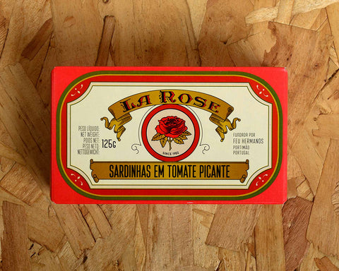 Sardines in spicy tomato in a rectangular box with a 1950s design on the front. La Rose is written on a gold banner above an image of a red rose. The tin has a red and gold border.