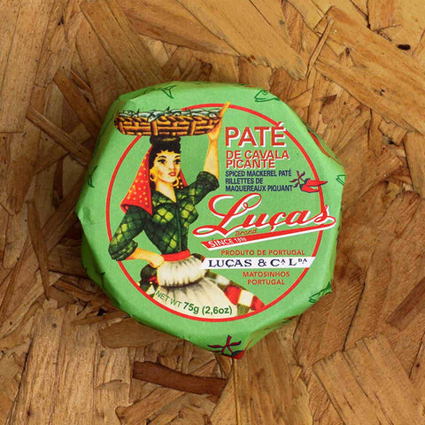 A round tin a green paper wrap with a picture of a woman carrying a basket of fish on her head next to the Luças logo written in red lettering.