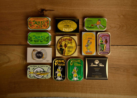 A selection of brightly-packaged tinned fish on a wooden backdrop