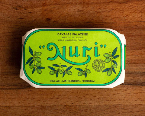 A tin of mackerel fillets in a green paper wrap with Nuri written in green lettering above some small olive branches.