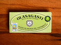 A green rectangular tin of Olasagasti anchovies in extra virgin olive oil against a wood background