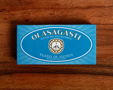 A tin of anchovies in light blue packaging with Olasagasti written in white lettering, on a wooden background 