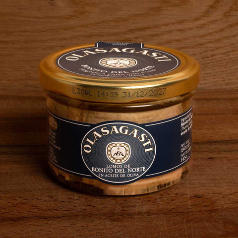A closed jar of tuna fillets with a gold lid and a blue label with Olasagasti written in white lettering, against a wood background