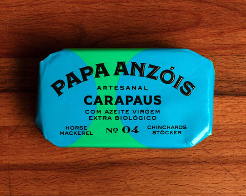 A tin of horse mackerel in organic extra virgin olive oil, with Papa Anzois labeled on top, presented in light yellow and green rectangular packaging. 