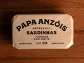 Smoked sardines in olive oil in light brown packaging, with Papa Anzóis displayed at the top.