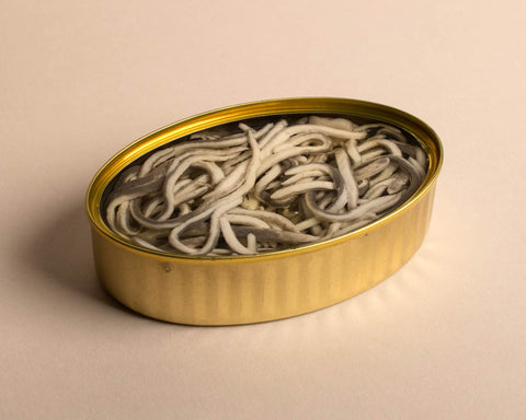 An opened tin of eels enriched in a succulent sauce. A gold trim throughout the whole tin. 