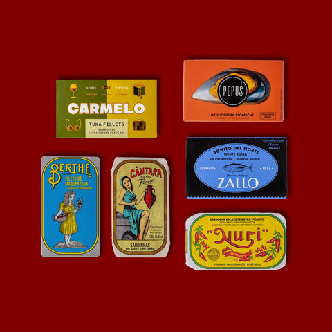 A selection of colourfully-packaged tinned sardines, tuna, mackerel, salmon and tasty sardines against a red background.
