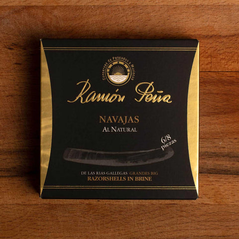 Razor clams in a square black and gold box with Ramón Peña written in raised gold lettering above a silver grey image of a razor shell.