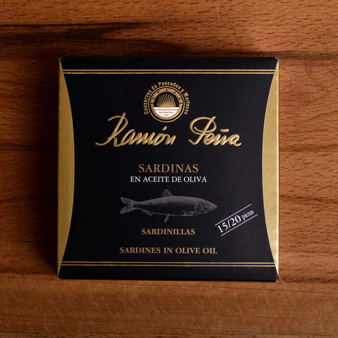 Sardines in olive oil in black and gold card packaging. Ramón Peña is written in raised gold lettering above a silver-grey image of a sardine.