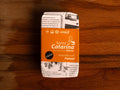 A tin of Santa Catarina tuna in newspaper-style packaging with an orange label against a wood background
