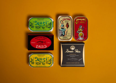A selection of colourfully-packaged tinned fish against a yellow background.