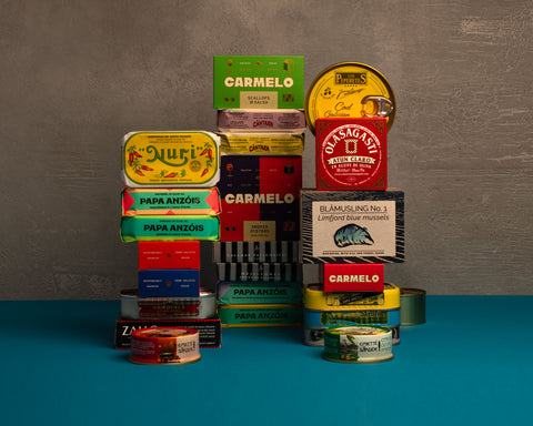Stack of various tins and boxes with different brand labels on a blue and gray background
