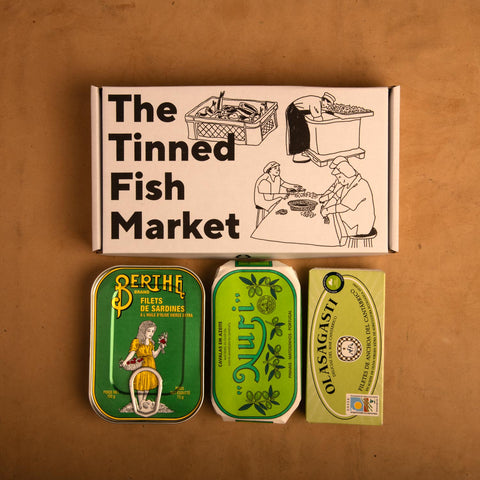 Three colourfully packaged tins of fish beneath an illustrated gift box