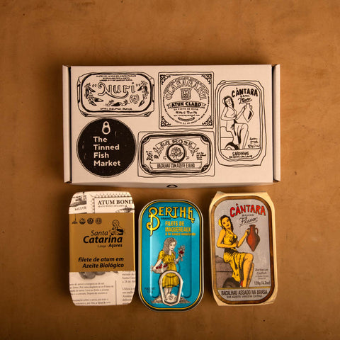 Three colourfully packaged Portuguese tins of fish beneath an illustrated gift box