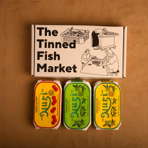 Three colourfully packaged tins of fish beneath an illustrated gift box