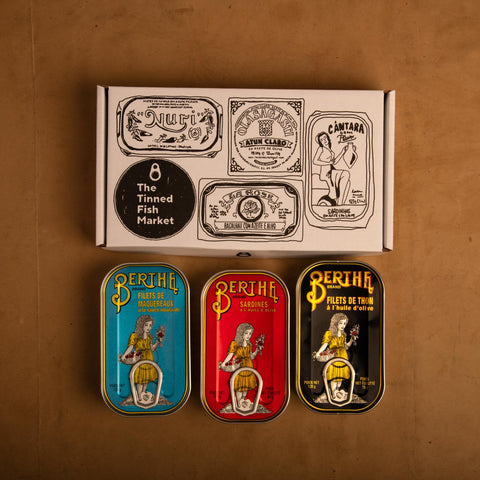 Three colourfully packaged Portuguese tins of fish beneath an illustrated gift box