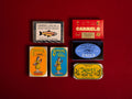 A selection of colourfully-packaged tinned 
sardines, tuna, mackerel, salmon and carmelo sardines against a red background.