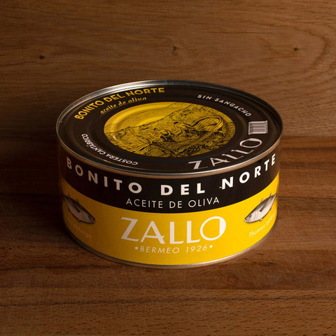 A large circular black and yellow tin of tuna with Zallo and Bonito del Norte written in white lettering on the lid and side 
